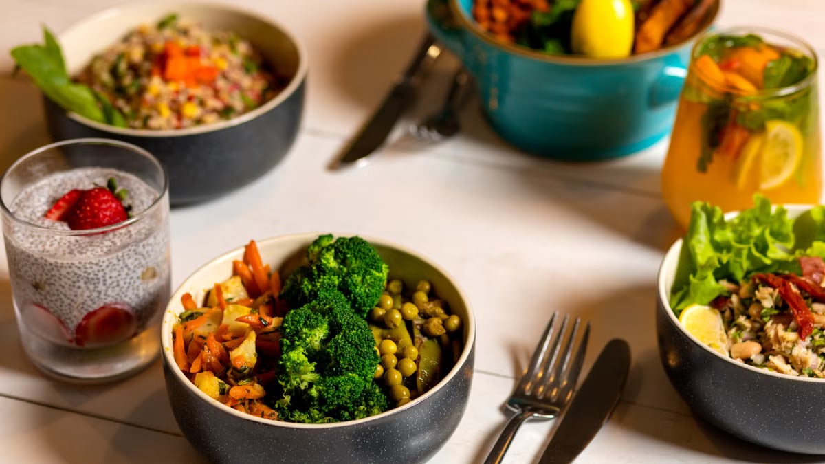 Delicious colorful bowls of salad and fresh beverages on a white table, perfect for healthy dining.